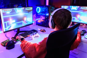Fotobehang Gaming Gamer playing online game on PC in dark room.  © Kannapat
