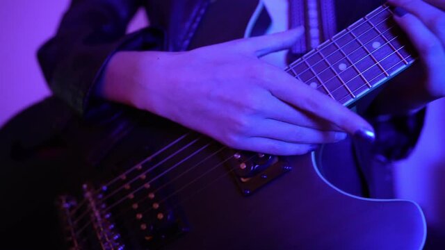 Girl playing on the semi-acoustic guitar. Close-up view.