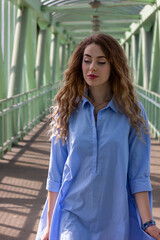 A girl in a blue nightgown walks across the bridge.