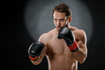 A man in Boxing gloves. A man Boxing on a black background. The concept of a healthy lifestyle