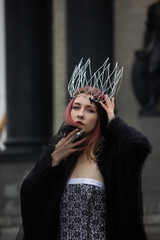 Russia, Moscow - 28/11/2020: Girl with pink hair in a dress and crown in the city.