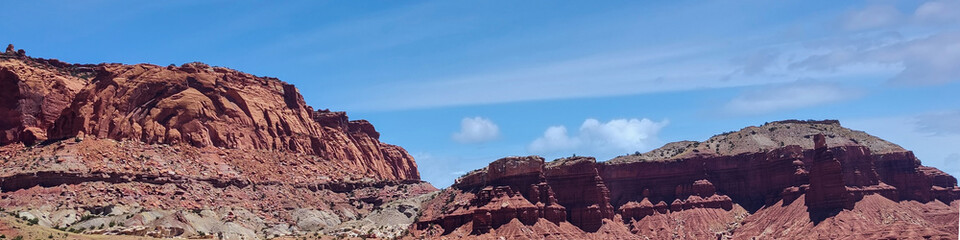 Amazing sandstone monoliths in a barren desert prairie on a blue partly cloudy summer day at Capitol Reef National Park in Torrey Utah