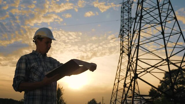 Power Engineer uses software technology to run a bastard project in the power industry. Working engineer with software application tablet. Telecommunications industry