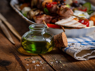 Bottle of olive oil on clay board over old wood background.