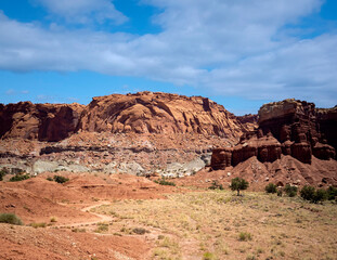 Fototapeta premium Amazing sandstone monoliths in a barren desert prairie on a blue partly cloudy summer day at Capitol Reef National Park in Torrey Utah