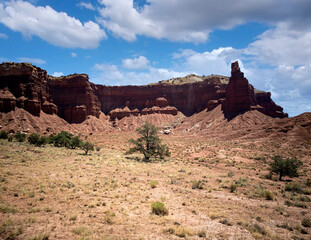 Fototapeta premium Amazing sandstone monoliths in a barren desert prairie on a blue partly cloudy summer day at Capitol Reef National Park in Torrey Utah
