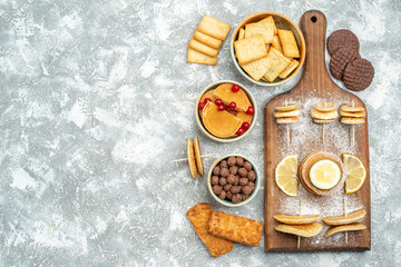 Simple pancakes with lemons on cutting board and cookies on blue background