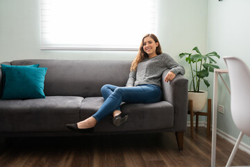 Obraz premium Beautiful young woman smiling and chilling on her couch