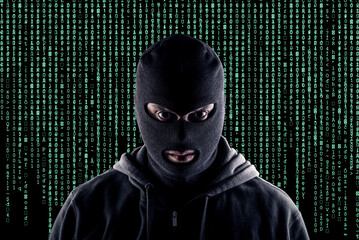 Masked cyber terrorist with black balaclava and hoodie in the dark
