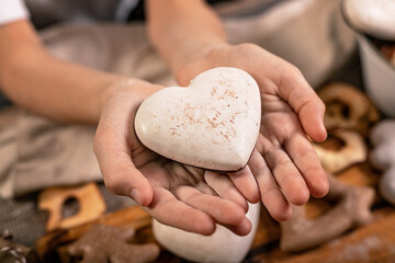 Girl hands hold heart shaped gingerbread. Wooden planks Christmas background