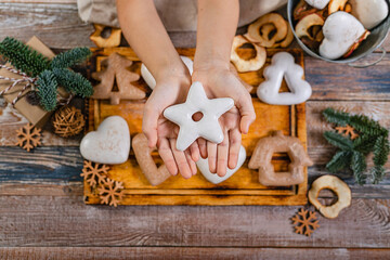 Girl hands hold gingerbread in the shape of a star. Wooden planks Christmas background. Top view