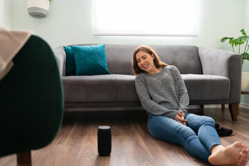 Obraz premium Smiling woman trying her new smart speaker at home