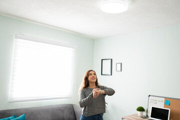 Woman using her smartwatch to turn on her smart light bulb