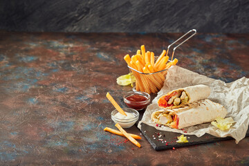 Eastern traditional shawarma, and French fries with sauces on slate