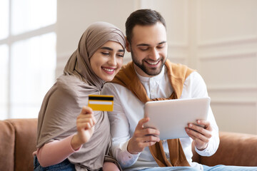 Muslim Couple Using Digital Tablet And Credit Card At Home