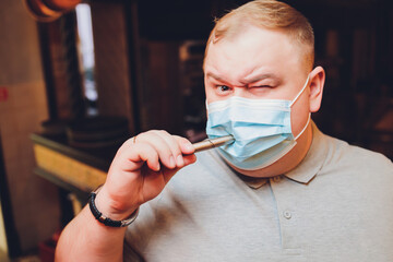 a man without clothes in a medical mask lights a pod e-cigarette through a mask, copy space, close...