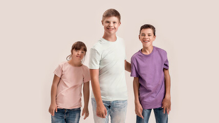 Three teenaged disabled children with Down syndrome and cerebral palsy smiling at camera while...