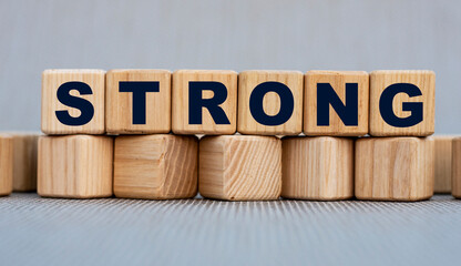 STRONG - word on wooden cubes on a beautiful gray background