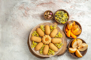 an overhead shot of cookies and bowls of dry flowers and fruits arount it on marble ground