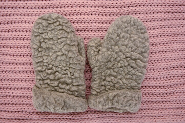 Gray wool mittens on pink knitted background