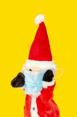 Hand puppet, glove puppet of santa Claus isolated on yellow Background with medical surgical protection Covid-19 mask. hand theater industry concept