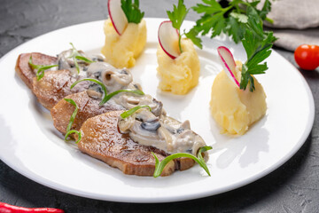 grilled beef tongue slices in mushroom sauce with mashed potatoes. on a white plate for the restaurant menu.