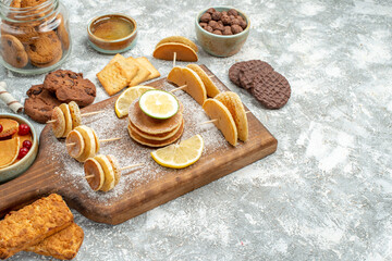 Top view of simple pancakes with lemons on cutting board and cookies honey on blue background