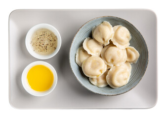 Boiled meat dumplings served with butter and vinegar with black pepper on gray tray isolated on white. Traditional Russian pelmeni. Top view.