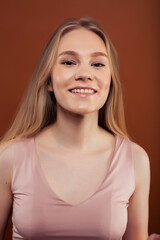 young pretty girl with blond hair posing cheerful on brown background, lifestyle people concept