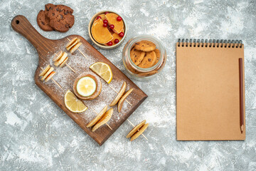 Notebook next to buttermilk pancakes with lemons on cutting board cookies on blue background