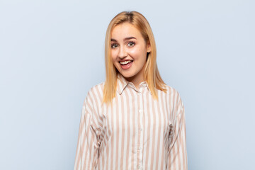 young blonde woman with a big, friendly, carefree smile, looking positive, relaxed and happy,...