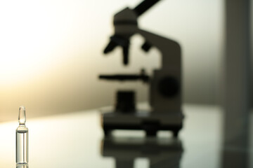Ampoule with a vaccine and a microscope on a glass table
