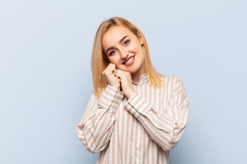 young blonde woman feeling in love and looking cute, adorable and happy, smiling romantically with...