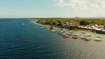 People snorkeling over coral reef with clear blue ocean water, top view. Moalboal, Philippines. People swim in the transparent sea between coral reefs. Summer and travel vacation concept.