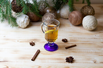 Glass of grog with gold rum, tea, honey, spices, lemon on wooden table with christmas background