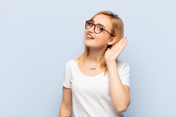 young blonde woman looking serious and curious, listening, trying to hear a secret conversation or...