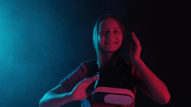 Portrait of a young beautiful girl in virtual reality glasses on a black background.