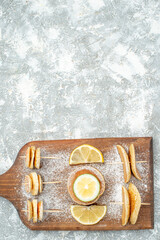 Vertical view of classic pancakes with lemons on wooden cutting board on blue background