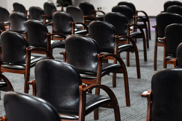 Empty black chairs stand in conference hall