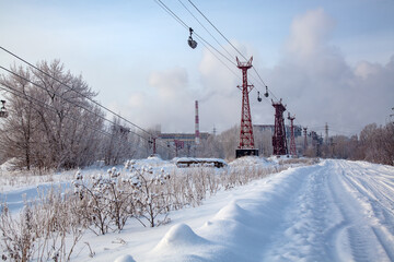 Industrial, winter landscape. Ropeway for transporting limestone surrounded by snowy trees. Carts transport the mined limestone to a baking soda plant.