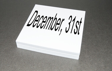 On a stack of square note paper is written December 31, the last day of the year, on a black background