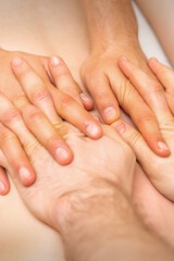 4 hands massage the patient back. Two masseurs doing massage. Closeup