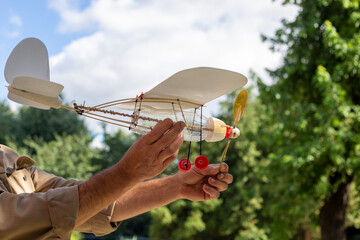 Airplane model with a propeller made from household waste plastic on a background of the sky in the hands of grandfather