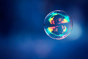 Large soap ball on a blue background. balloon in the blue sky. Large soap dish, the world inside a soap ball with reflection inside. close-up