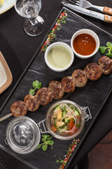 Tasty kofta kebab with vegetable salad and sauce on the table