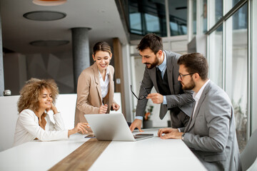Group of young business people working and communicating while sitting at the office desk together