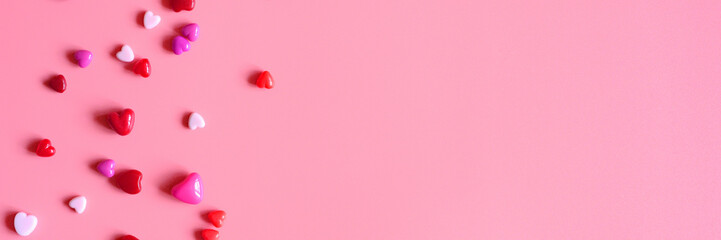 a heap of heart shaped glossy beads in different pink shades on a pink background. banner. space for text