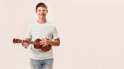 Cheerful disabled boy with Down syndrome smiling while playing ukulele, standing isolated over white background