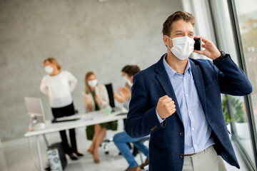 Young business man using mobile phone while wear protective masks to prevent  corona viruus at office space