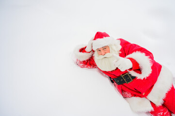 Happy santa claus lying in the snow and fooling around